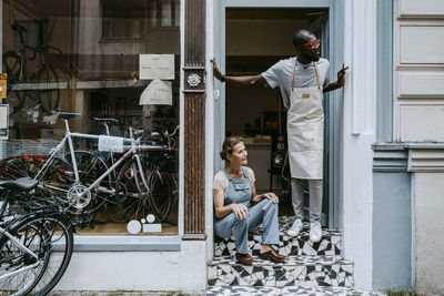 Senior owner and colleague looking away against bicycle shop