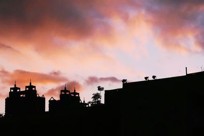 Low angle view of silhouette buildings against sky