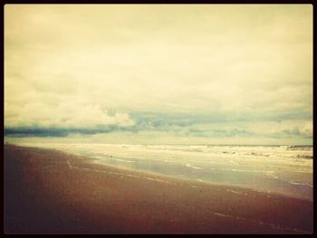 Scenic view of beach against cloudy sky