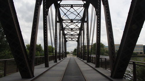 Footbridge against cloudy sky