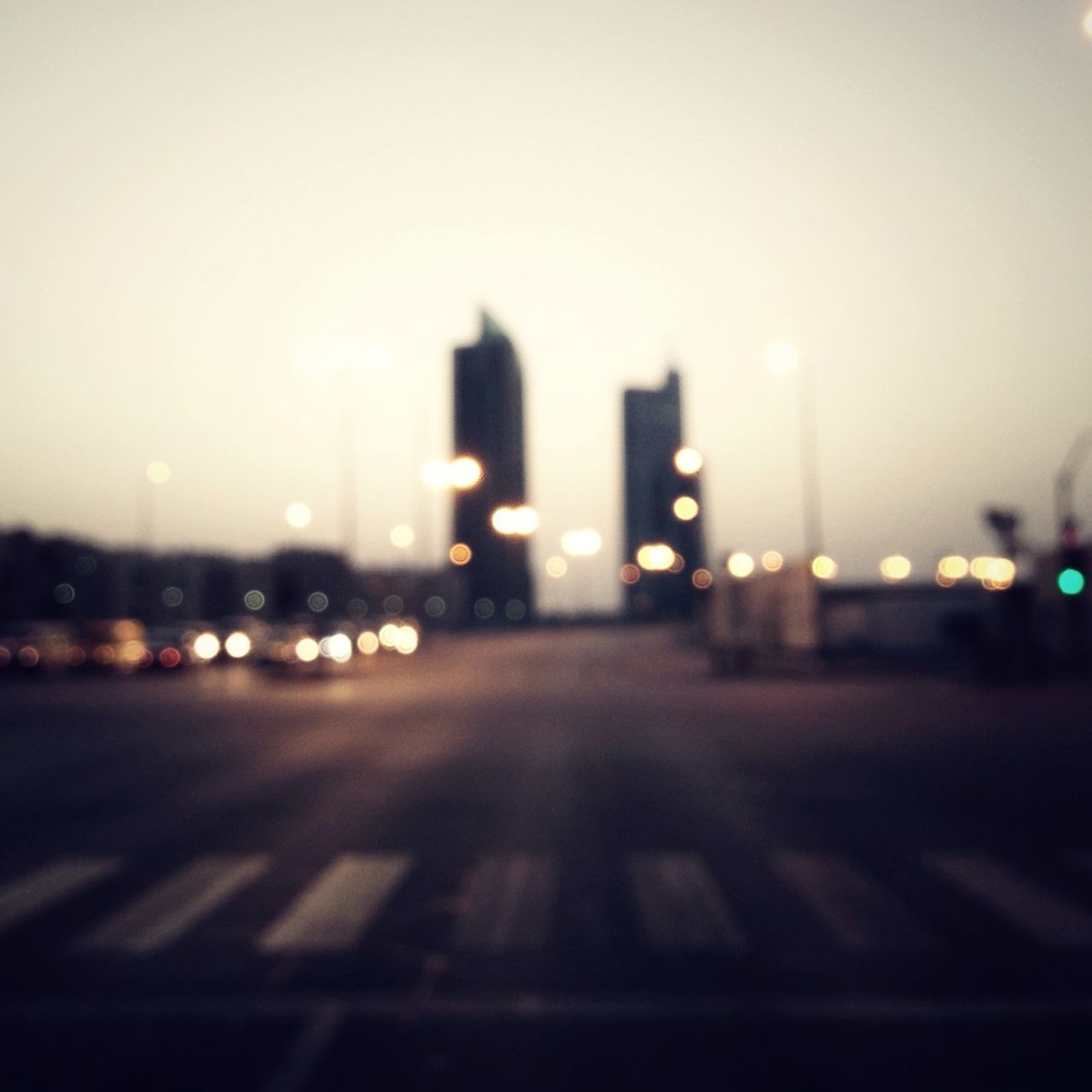 illuminated, road, defocused, night, street, city, transportation, building exterior, surface level, the way forward, clear sky, architecture, road marking, built structure, street light, copy space, lighting equipment, outdoors, selective focus, diminishing perspective