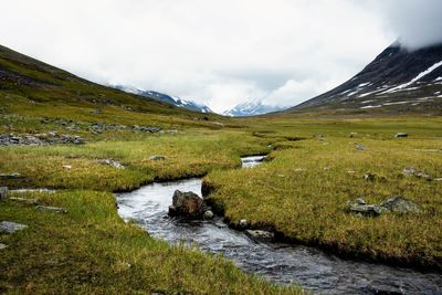 Scenic view of green landscape and mountains against sky