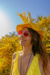 Young woman wearing sunglasses while standing against trees