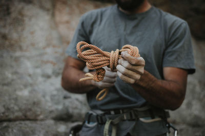Midsection of man tying rope