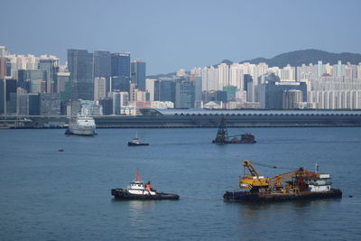 Sailboats in sea against buildings in city