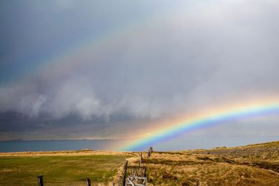 Scenic view of rainbow over land against sky