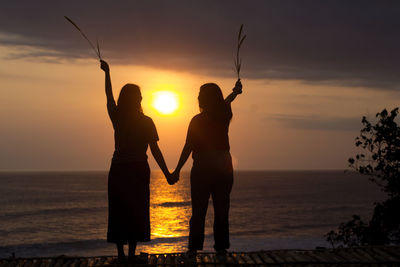 Silhouette woman standing on beach against sky during sunset