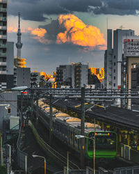 High angle view of railroad tracks by buildings against sky during sunset