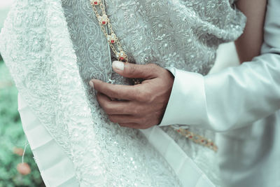 Midsection of groom with bride