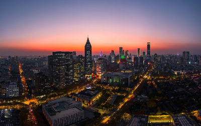 Aerial view of illuminated buildings in city during sunset