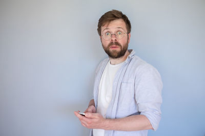 Portrait of young man using smart phone against white background