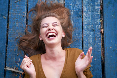 High angle view young woman laughing while lying on wood paneling