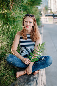 Portrait of young woman sitting by plants