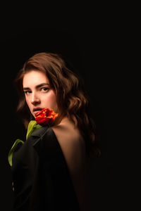 Portrait of young woman holding sparkler against black background