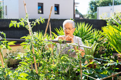 Portrait of young woman sitting by plants