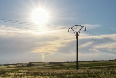 Electricity pylon on field against sky