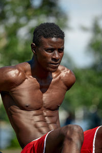 Portrait of shirtless young man standing outdoors