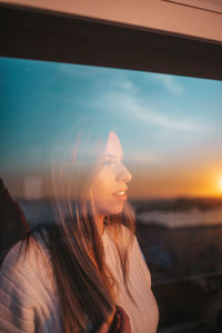 Woman looking at sea against sky during sunset