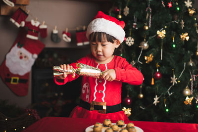 Cute boy holding christmas present by food 