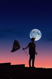 Full length of silhouette woman standing against moon at sunset