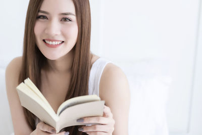 Portrait of a smiling young woman reading book