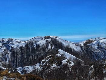 Scenic view of snowcapped mountains against clear blue sky