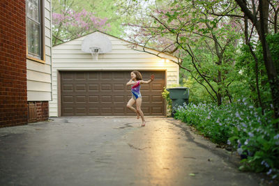 A little girl happily dances barefoot in a leotard in her driveway