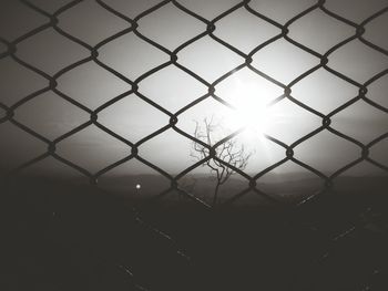 Landscape against sky seen through chainlink fence