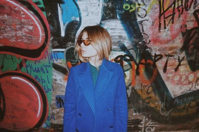 Woman standing by graffiti on wall