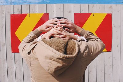 Rear view of man standing in front of woman against wall