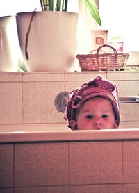 Portrait of cute baby with pink headwear in bathtub