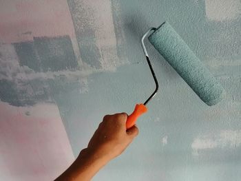 Close-up of hand holding umbrella against wall