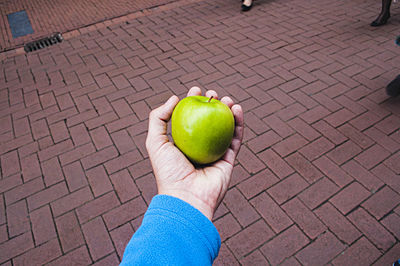 High angle view of person holding apple on street