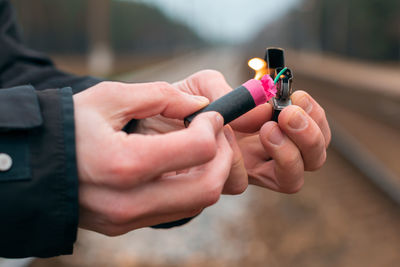 Midsection of man holding burning firecracker