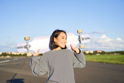 Side view of young woman standing against sky