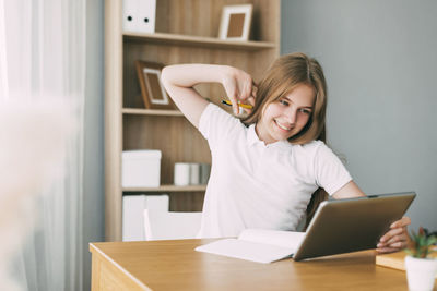 Portrait of smiling woman using phone while sitting on table