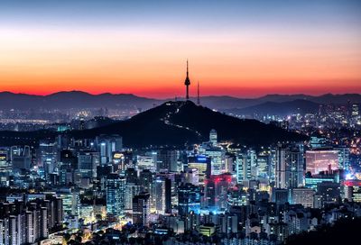 Illuminated city against sky during sunset