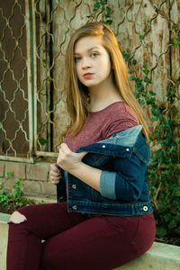 Portrait of young woman sitting on railing