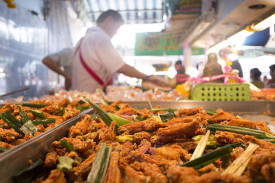 Close-up of fried chicken with lemon grass in tray for sale