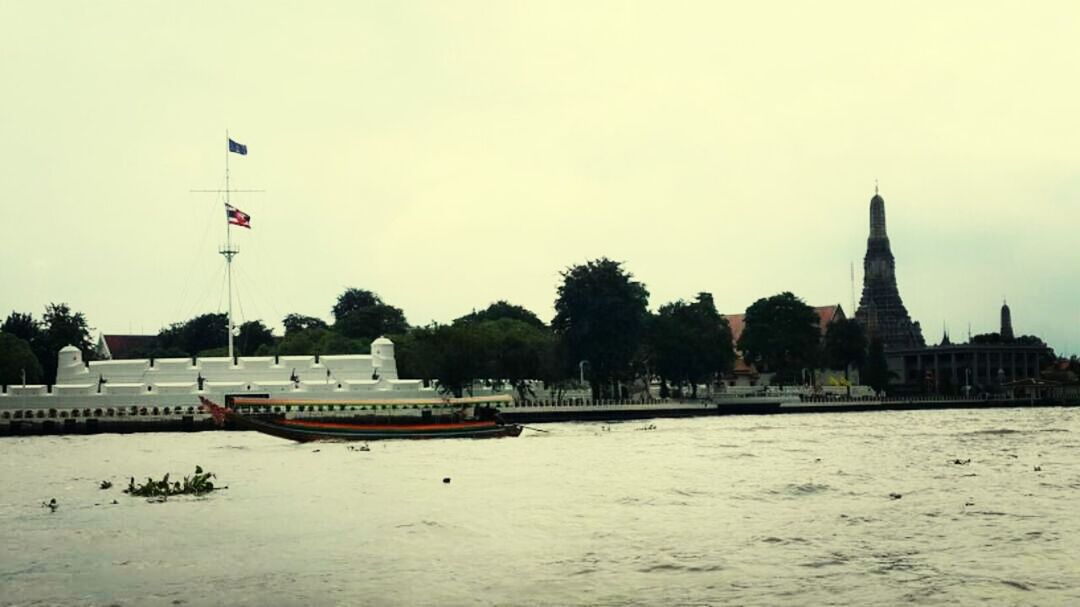 building exterior, architecture, built structure, water, waterfront, sky, tree, clear sky, sea, flag, river, incidental people, nautical vessel, outdoors, transportation, travel destinations, copy space, nature, city, rippled