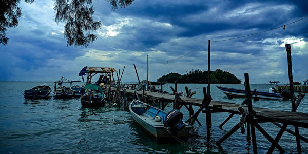 Fishing boats moored in sea against sky