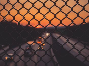 Highways seen through chainlink fence during sunset