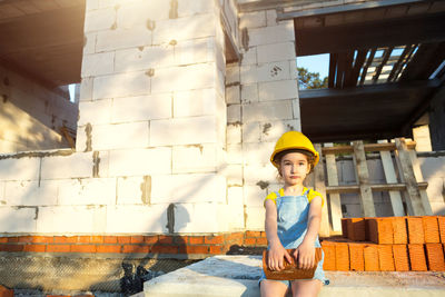 Cute girl wearing hard had holding brick at construction site