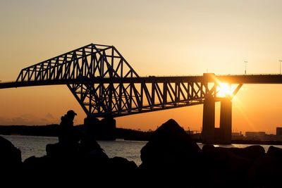 Silhouette people on bridge against sky during sunset