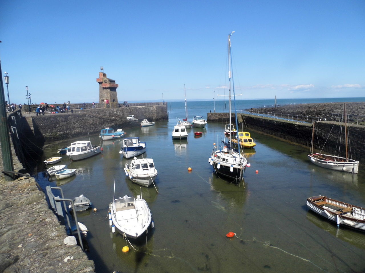 SAILBOATS MOORED ON SHORE AGAINST BLUE SKY