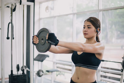 Young woman exercising with weight at gym