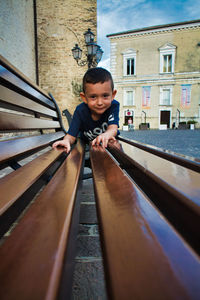 Portrait of cute boy on bench in city