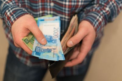 Midsection of man holding wallet with paper currencies