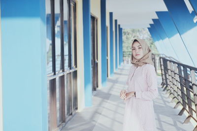 Portrait of woman wearing hijab while standing on corridor