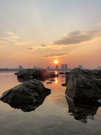 Rocks on sea against sky during sunset